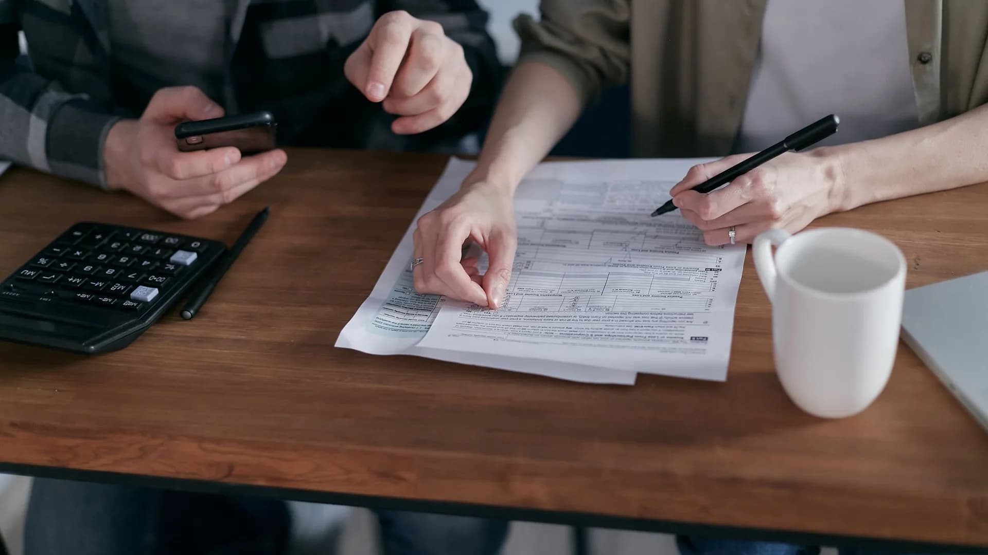Para analizuje dokumenty finansowe z kalkulatorem przy stole